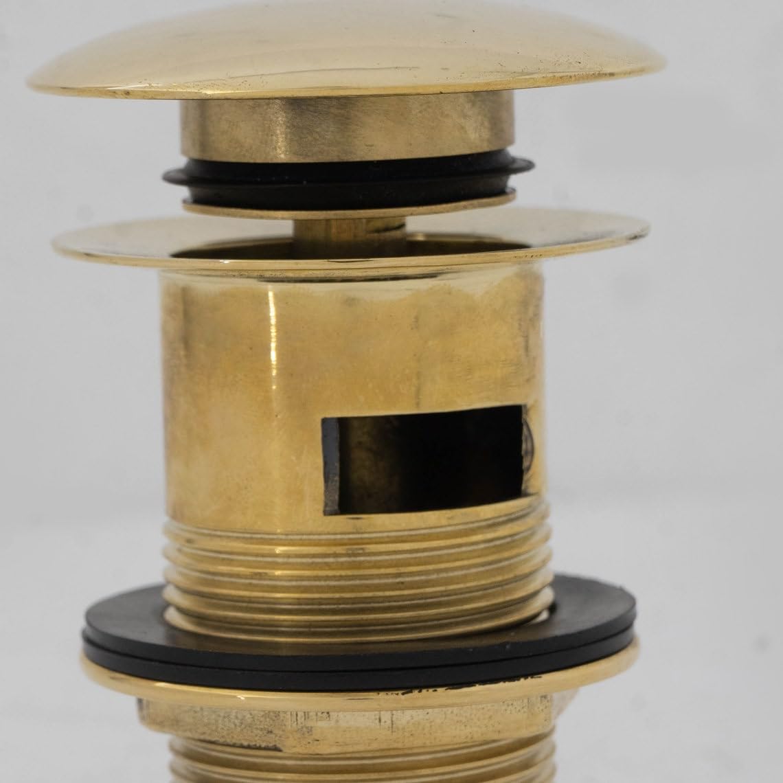 Precision machined solid brass pop-up basin stopper mechanism with internal spring cartridge and overflow channel.